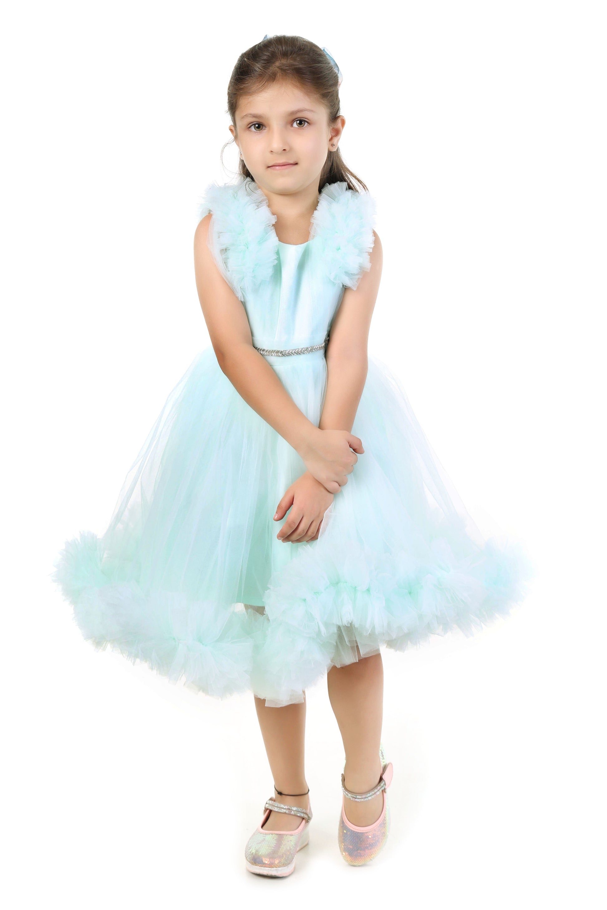 Young girl wearing a mint color dress with ruffled details on a white background