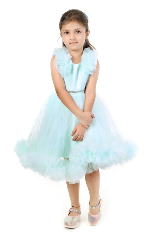 Young girl wearing a mint color dress with ruffled details on a white background