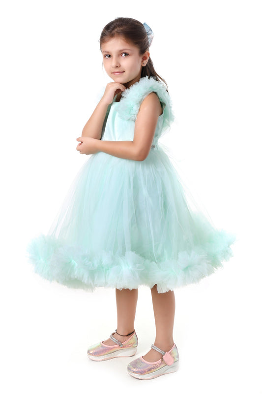Young girl wearing a mint color dress with ruffled details on a white background
