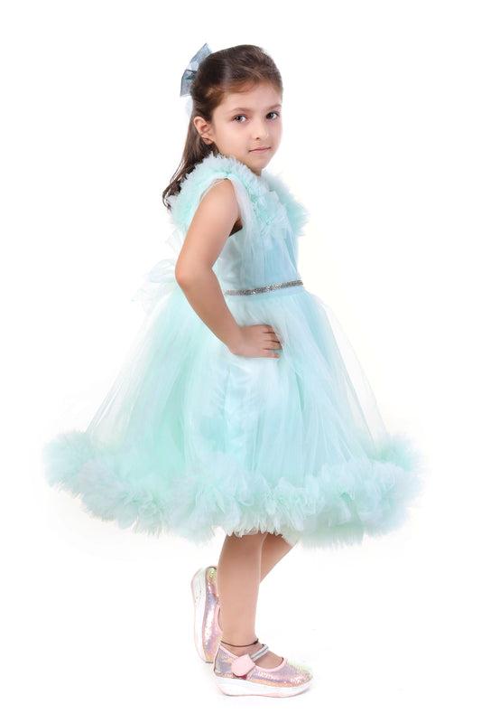 Young girl wearing a mint color dress with ruffled details on a white background
